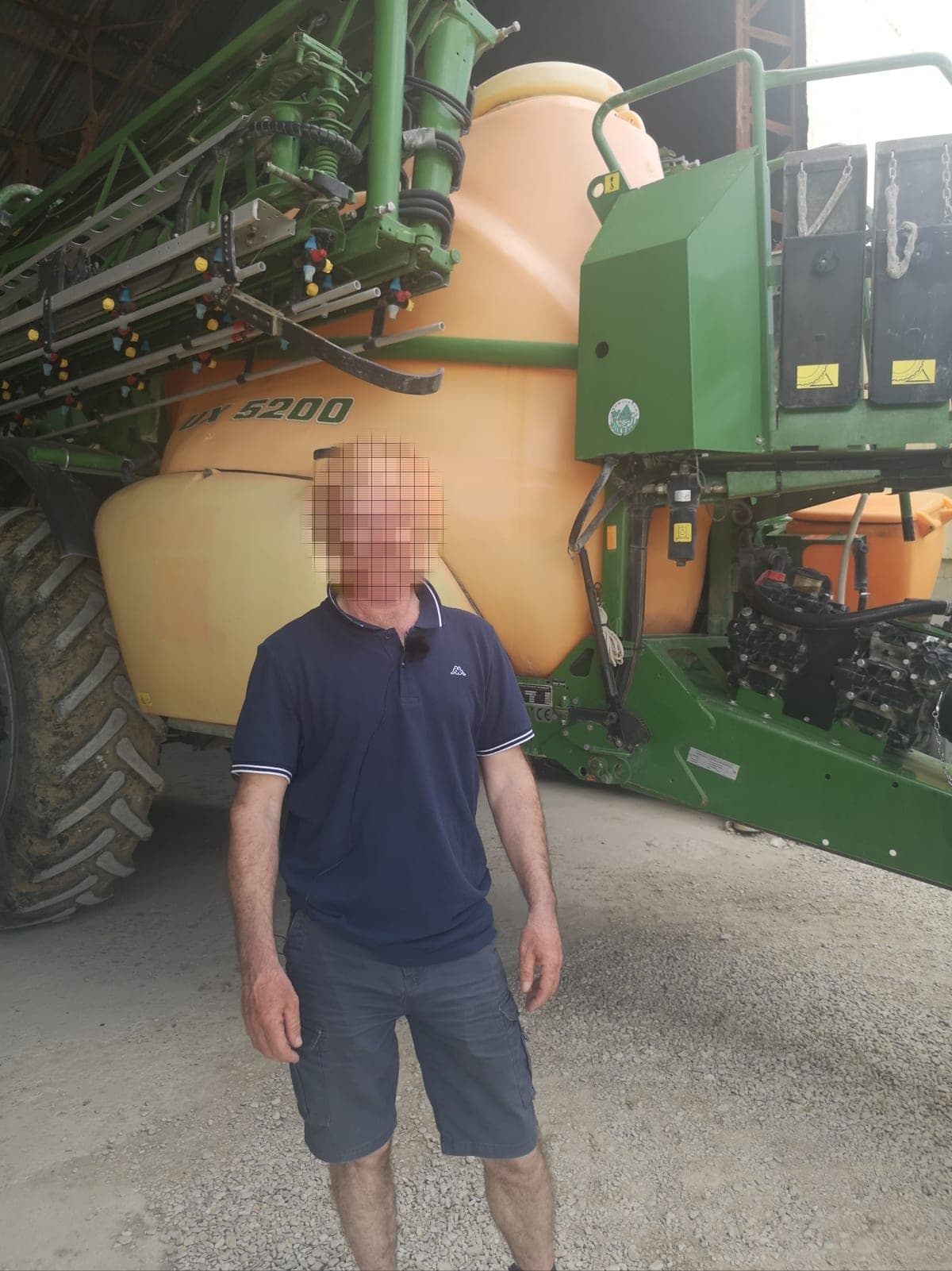 A farmer standing in front of his Amazone boom sprayer in the barn